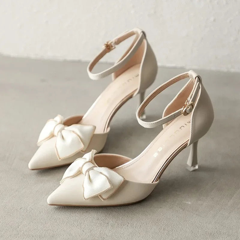 Elegant pearl women's high heels with pointed toes, gold-trimmed bow detail, and ankle strap design."